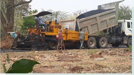 Bituminous paving equipment loading from a tipper on site